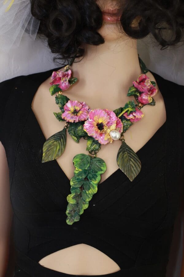 A woman wearing a necklace with pink flowers.