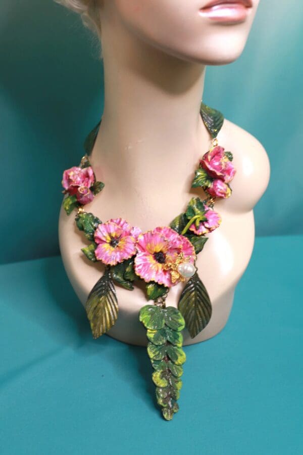A necklace with pink flowers and green leaves.
