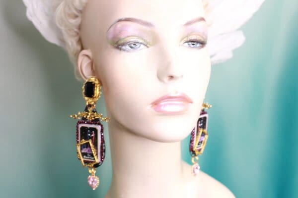 A mannequin wearing earrings with pink and black stones.