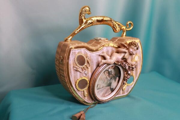 A pink purse with gold trim and a clock on the front.