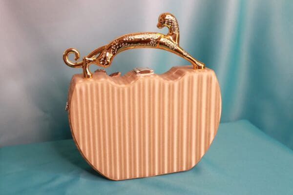 A pink purse with gold handle and top