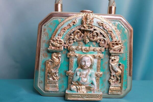 A blue and gold purse with a statue of a person.