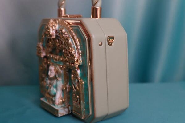 A small green and gold box with a chain on top of it.