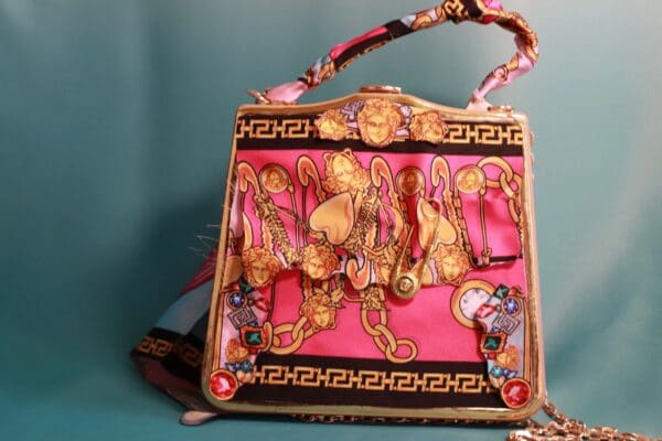 A pink purse with gold and black designs on it.