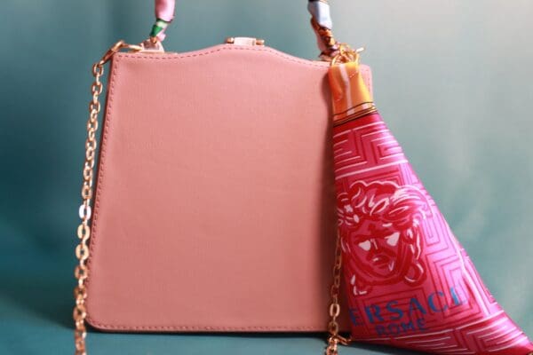A pink purse and bottle of lotion on the table.