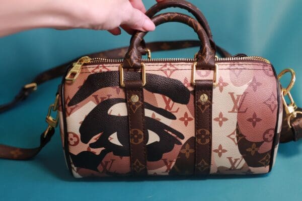 A person holding onto the strap of a louis vuitton bag