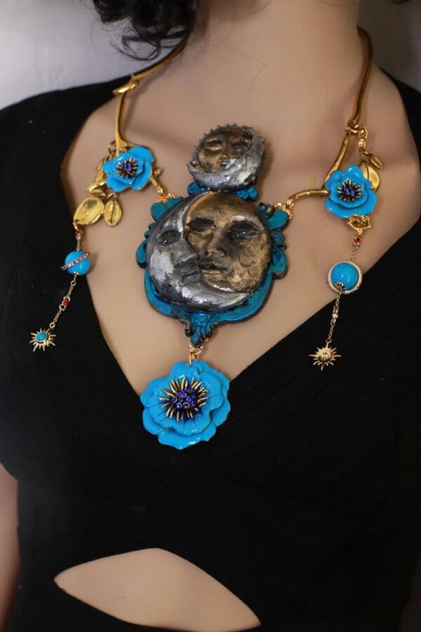 A woman wearing a necklace with blue flowers and a face.