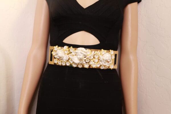 A woman wearing a black dress with gold and white jewelry.
