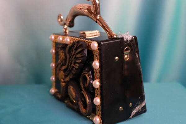A black purse with gold trim and a horse handle.