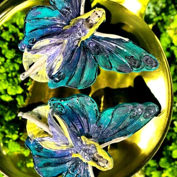 Two blue butterflies sitting on top of a gold bowl.