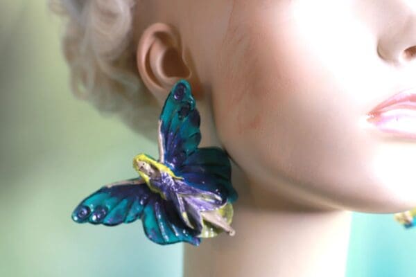 A woman wearing blue and yellow butterfly earrings.