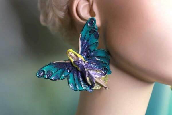 A woman wearing blue and purple butterfly earrings.
