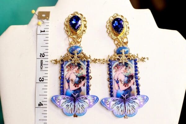 A pair of earrings with blue beads and a butterfly.