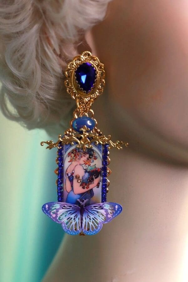 A woman wearing blue earrings with a picture of a butterfly.