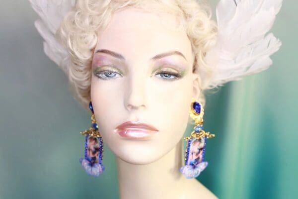 A mannequin wearing earrings with blue and white feathers.