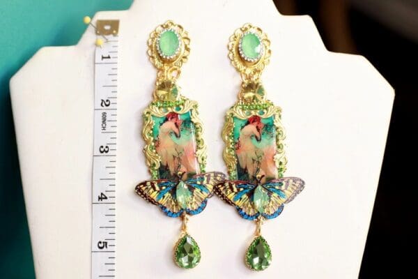 A pair of earrings with a bird and butterfly on them.