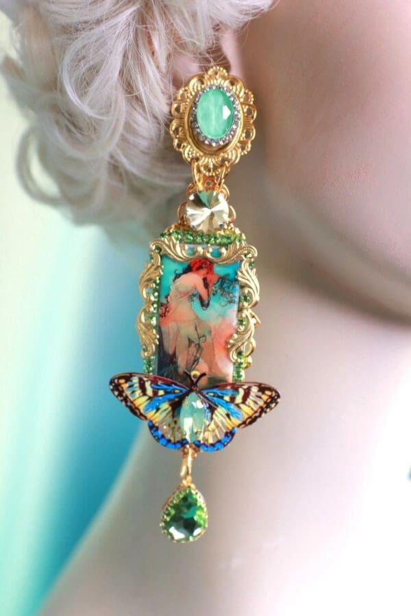 A woman wearing a pair of earrings with a bird on it.