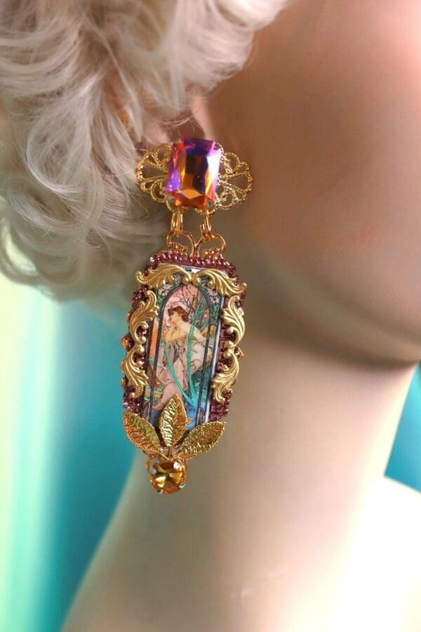 A woman wearing a pair of earrings with a picture on it.