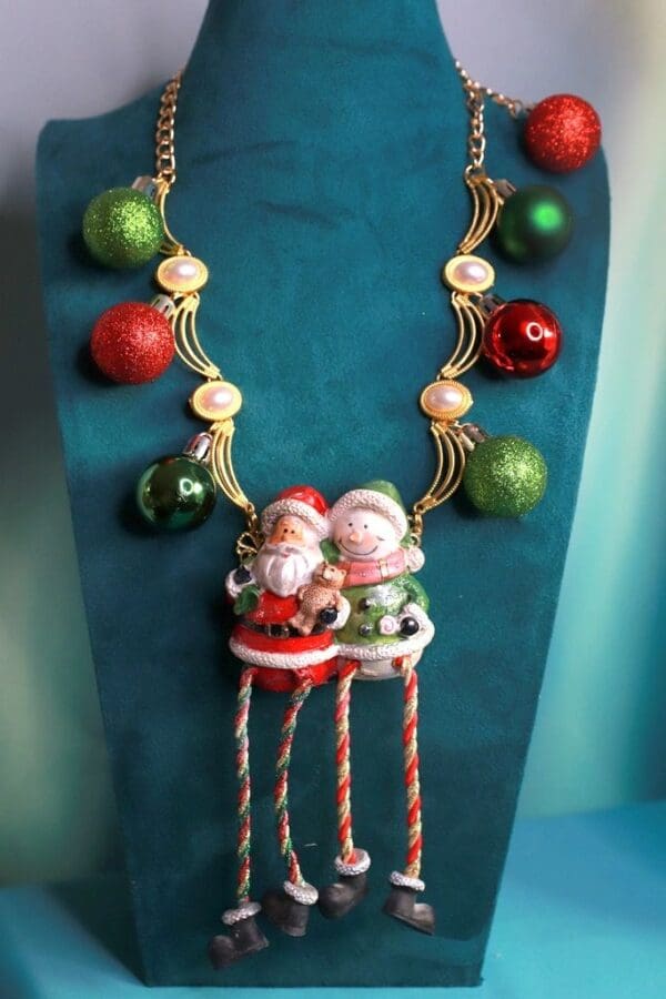 A necklace with two santa clause and christmas ornaments.