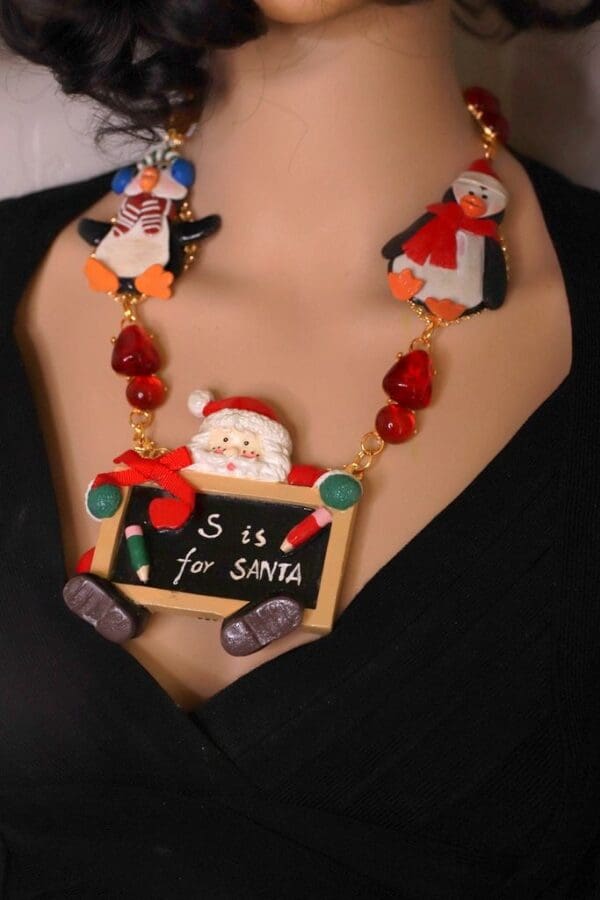 A woman wearing a necklace with santa and penguins on it.