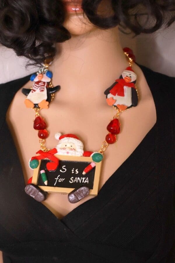 A woman wearing a necklace with santa and penguins on it.