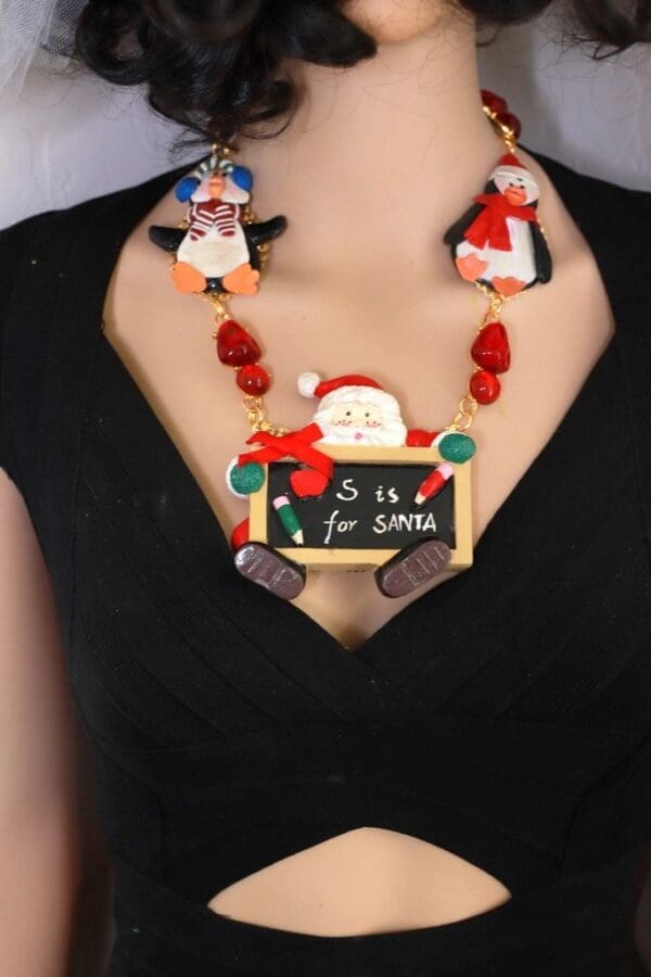 A woman wearing a necklace with santa and penguins on it.