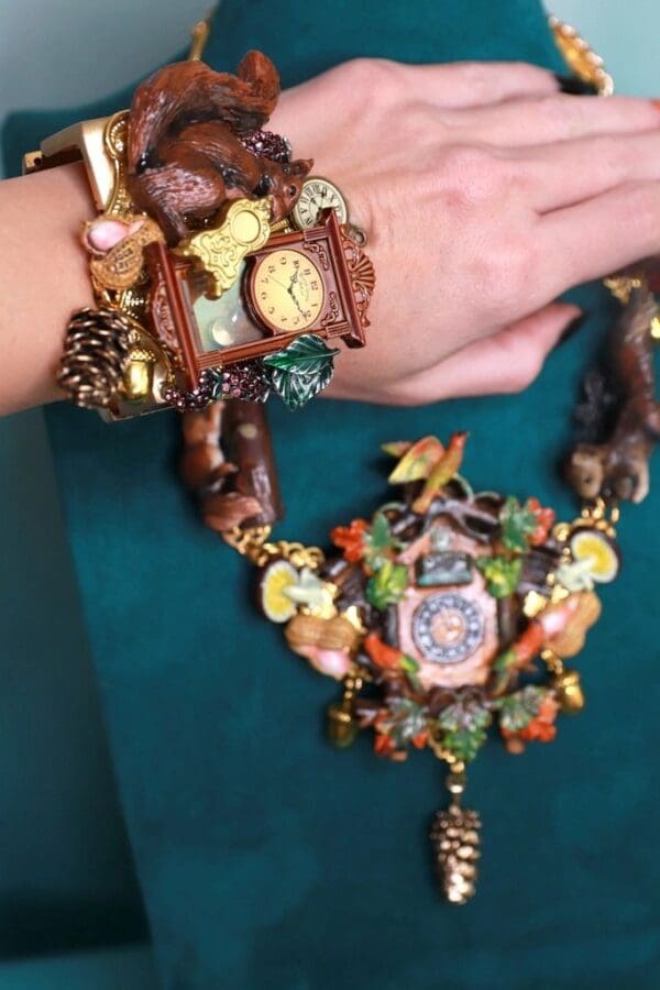 A woman 's hand wearing a watch and a necklace.