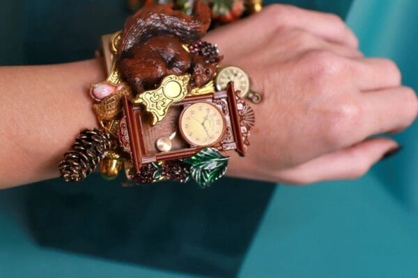 A woman 's wrist with a clock and some pine cones