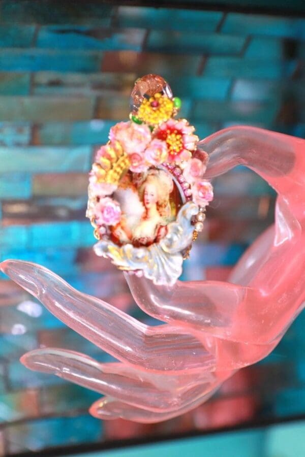 A pink hand holding a colorful flower necklace.