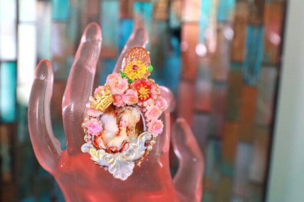 A hand with flowers on it is shown in front of a blurry background.