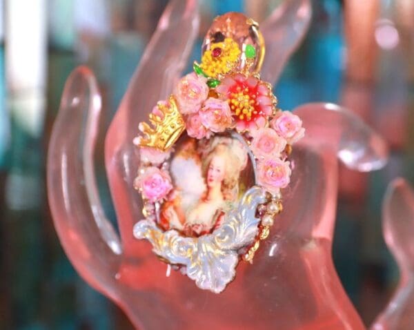 A hand holding a pink object with flowers on it.