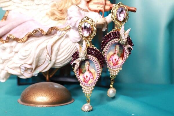 A pair of earrings with pearls and a doll