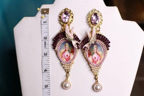 A pair of earrings with a bird and a crown on them.