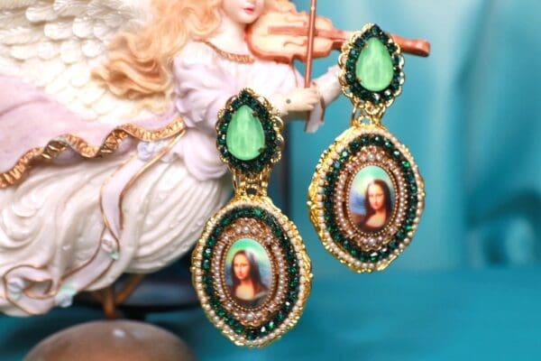 A pair of earrings with green stones and a picture.