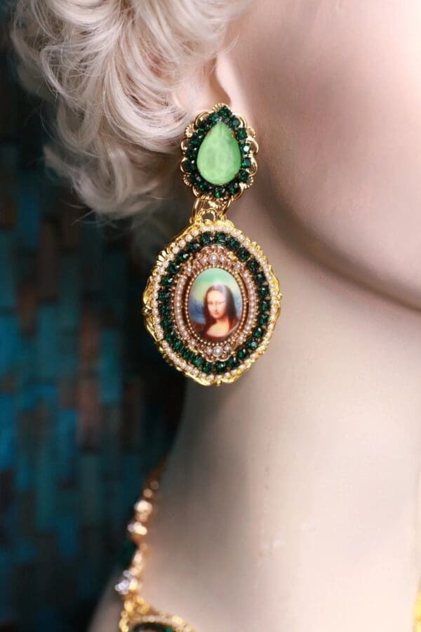 A woman wearing earrings with a painting on it.