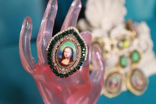 A pink hand holding a green and white ring.