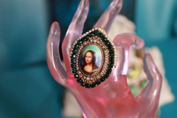 A pink hand holding a picture of mona lisa.