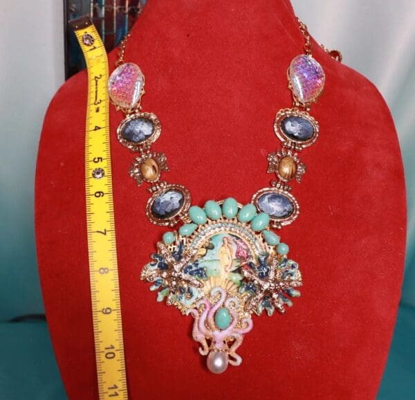 A red velvet display case with a necklace and measuring tape.