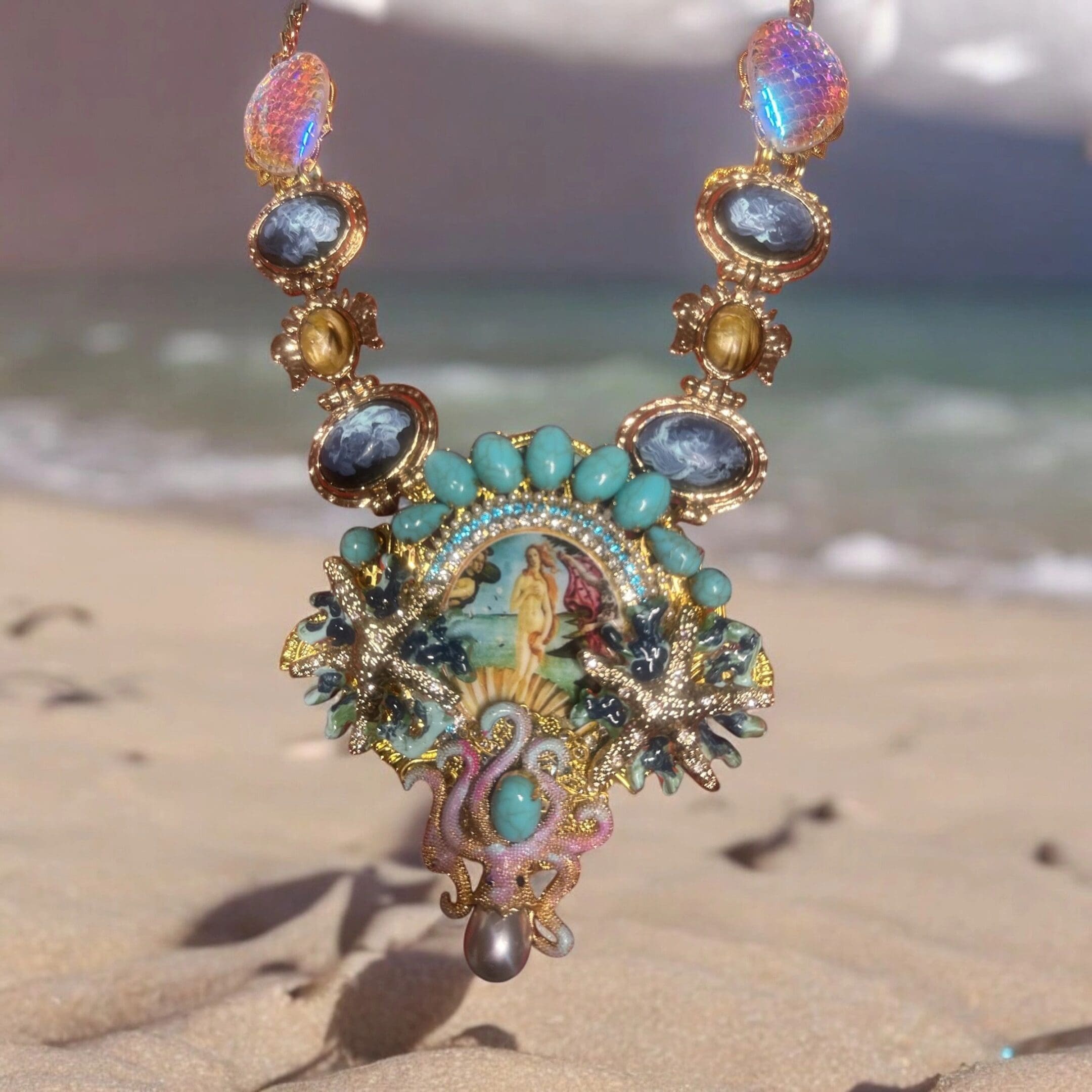 A necklace with sea creatures and gemstones on the beach.