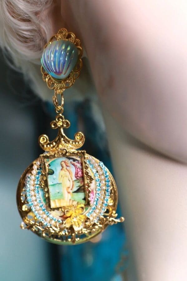 A woman wearing earrings with a picture of a mermaid.