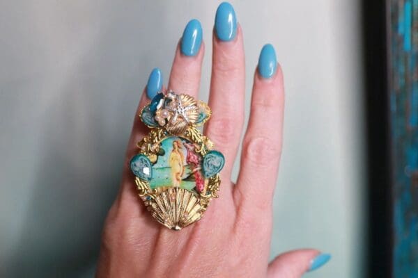 A woman 's hand with blue nails and a ring