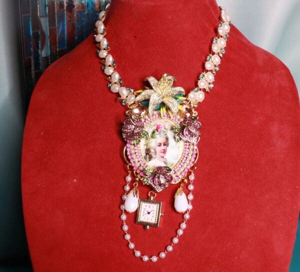 A red velvet display with a necklace and watch on it.