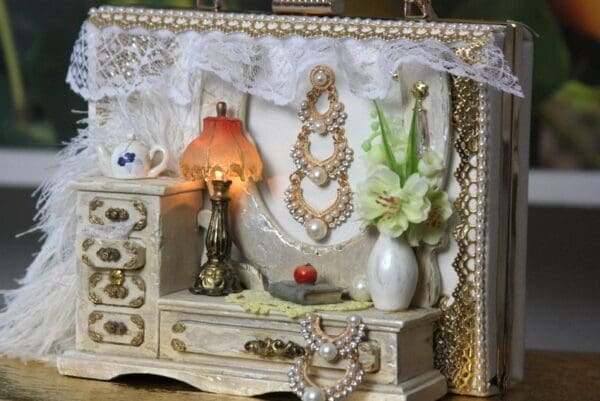 A white dresser with a lamp and vase on top of it.