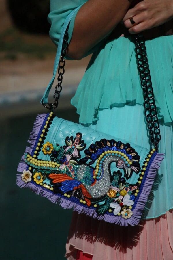 A woman in blue dress holding onto a purse