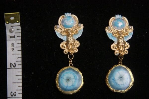 A pair of earrings with blue and gold accents.