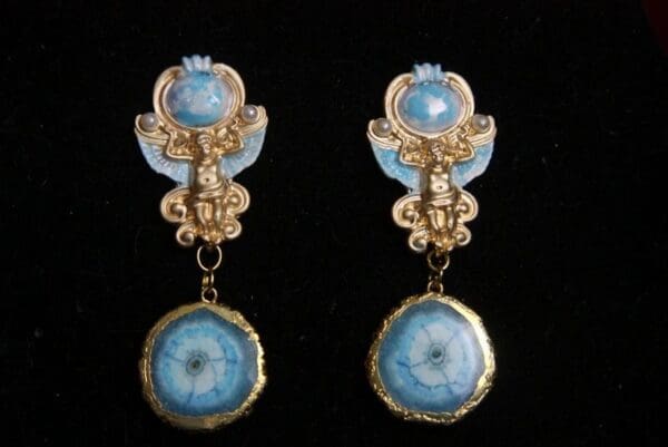 A pair of earrings with blue and gold accents.