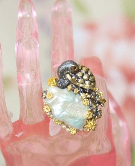 A close up of a ring on top of a pink glass