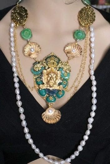 A woman wearing a necklace with pearls and green stones.
