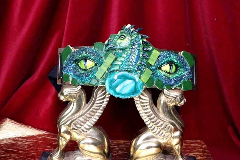 A dragon bracelet sitting on top of two gold statues.