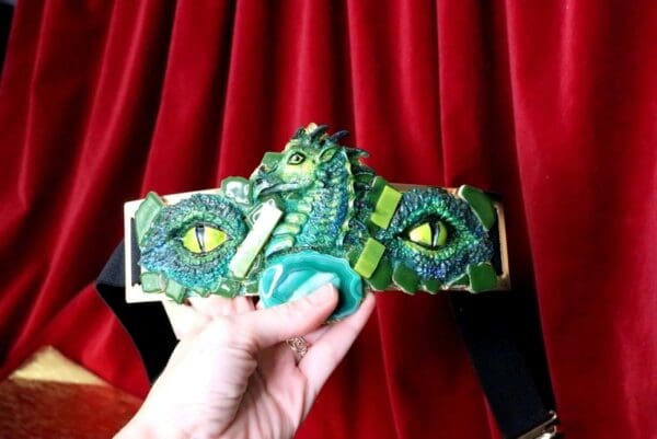 A hand holding a dragon belt with eyes.